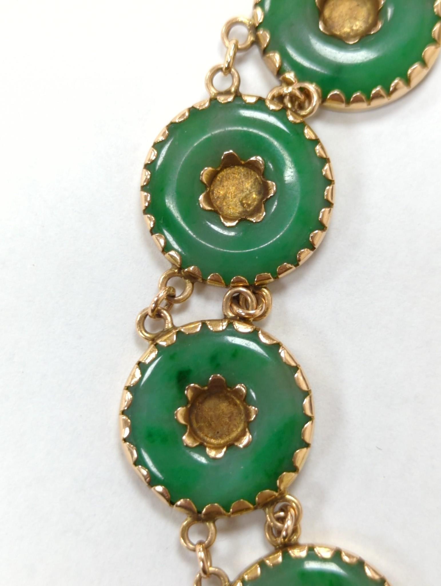 A Chinese yellow metal (stamped 18) and pierced eight stone jade disc set bracelet, with central Chinese characters, 16.5cm approx. gross weight 27.7 grams.